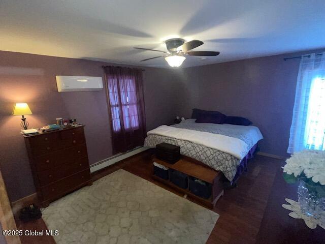 bedroom with baseboards, a wall mounted air conditioner, ceiling fan, and baseboard heating