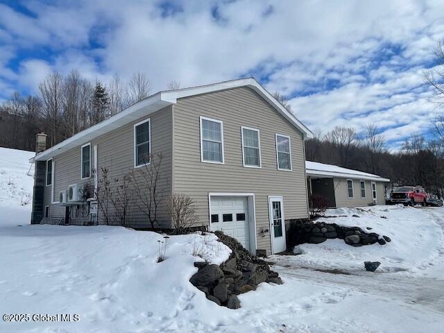 view of snowy exterior with an attached garage