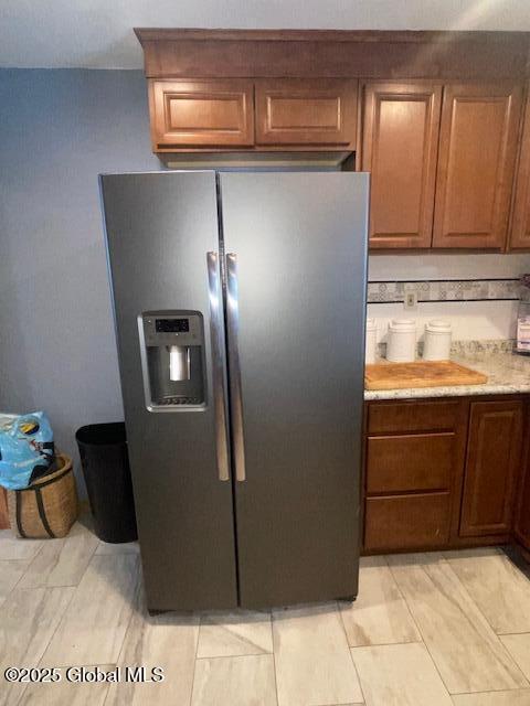 kitchen with brown cabinets, light countertops, and stainless steel refrigerator with ice dispenser