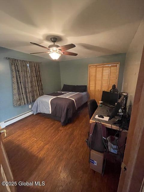 bedroom with a ceiling fan, baseboard heating, and wood finished floors