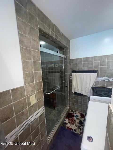 bathroom with a shower stall and tile walls