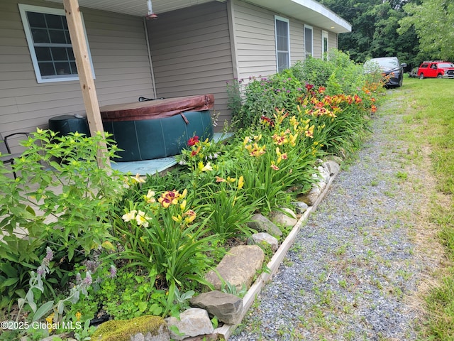 view of yard with driveway and a hot tub