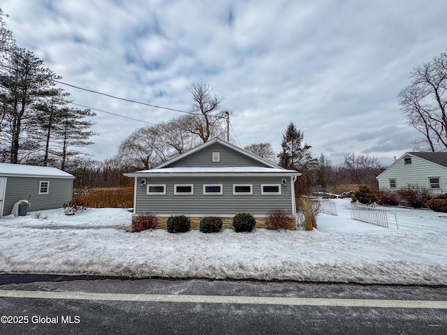 snow covered property featuring an outdoor structure and fence