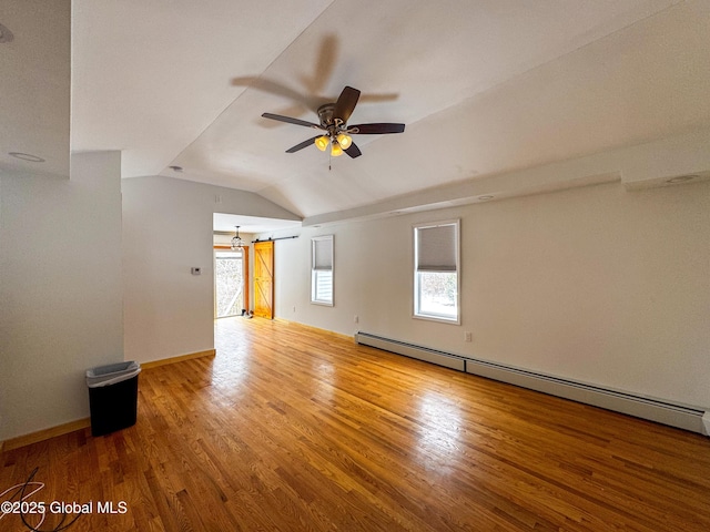 spare room featuring lofted ceiling, baseboard heating, a ceiling fan, wood finished floors, and baseboards