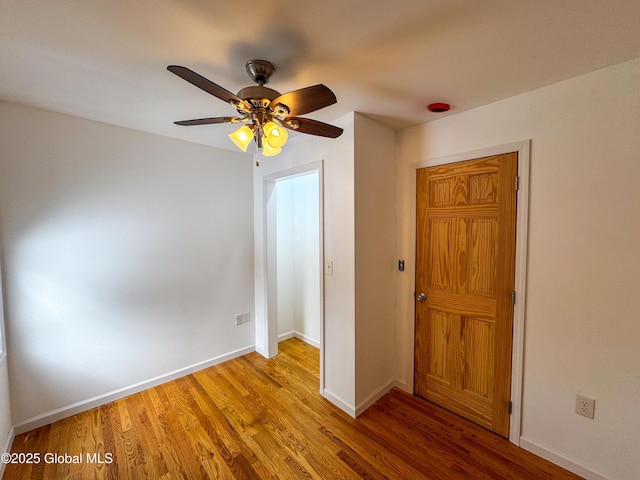 interior space featuring a ceiling fan, baseboards, and wood finished floors