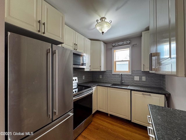 kitchen featuring dark wood-style floors, appliances with stainless steel finishes, decorative backsplash, and a sink