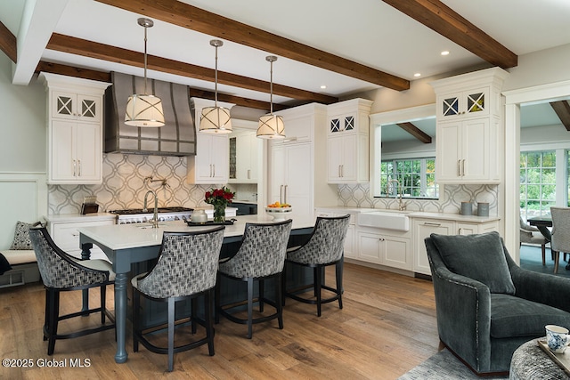 kitchen with a sink, glass insert cabinets, a kitchen bar, and light countertops