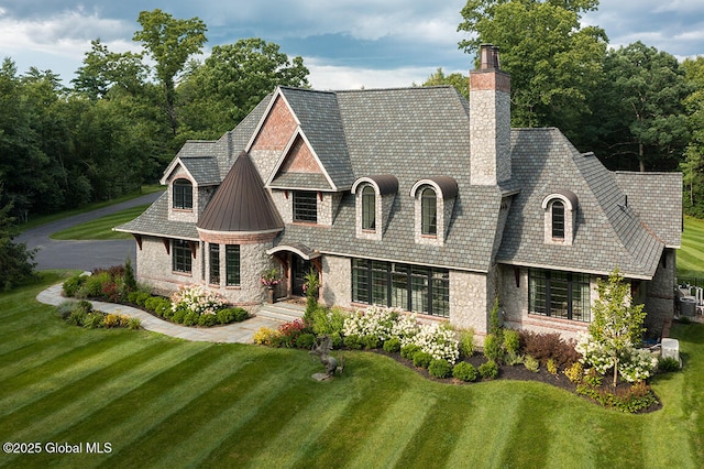 view of front facade with a front lawn, a high end roof, a chimney, stone siding, and a standing seam roof
