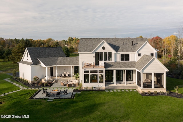 rear view of property with a balcony, an outdoor fire pit, a sunroom, a patio area, and a lawn