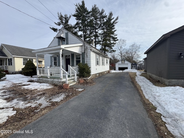 view of front facade with a garage, covered porch, driveway, and an outdoor structure