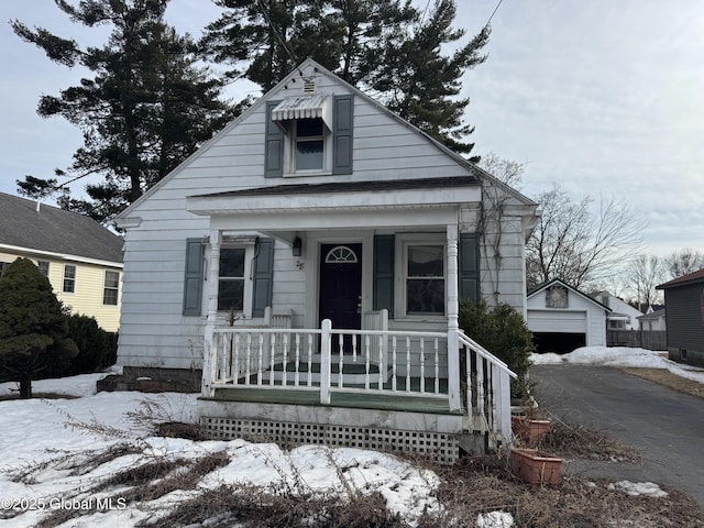 bungalow featuring a porch, an outbuilding, and a garage