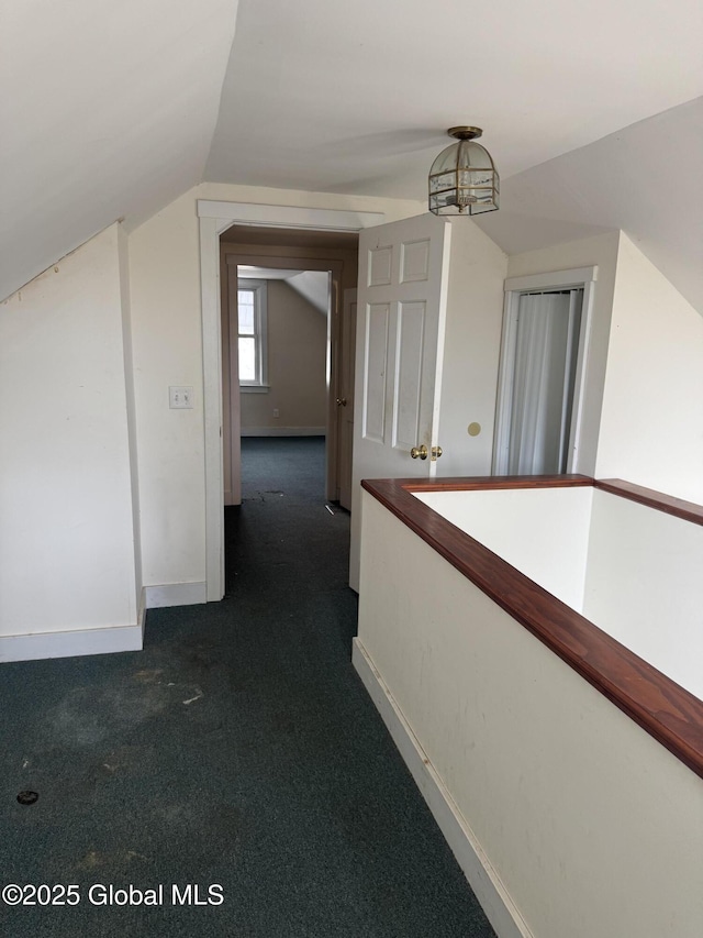 additional living space with vaulted ceiling, baseboards, and dark colored carpet