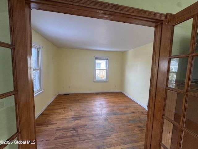 empty room with baseboards and hardwood / wood-style flooring