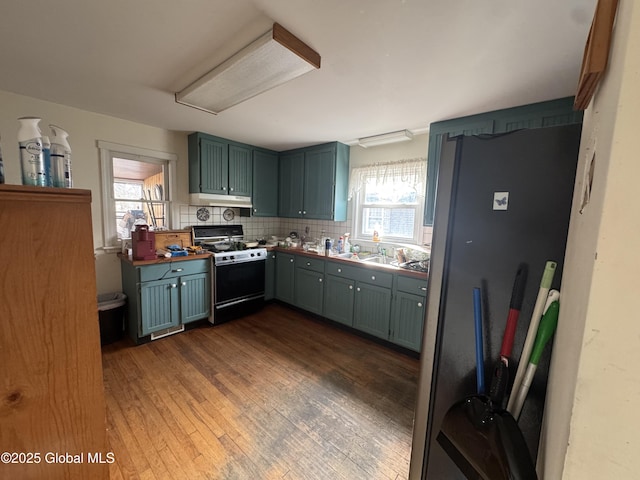 kitchen with under cabinet range hood, range with gas cooktop, dark wood-style flooring, and decorative backsplash