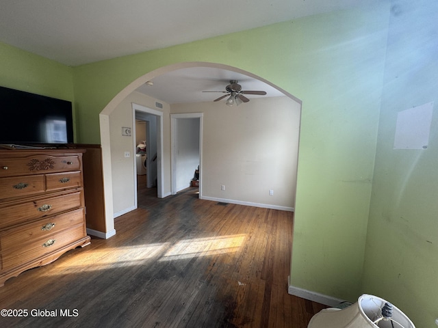 interior space with wood finished floors, visible vents, a ceiling fan, baseboards, and arched walkways