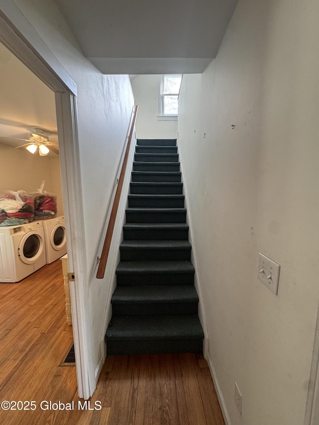 stairs with a ceiling fan, wood finished floors, washing machine and dryer, and baseboards