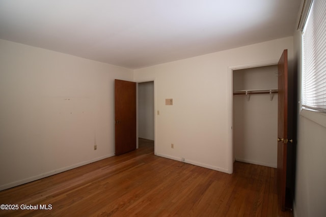 unfurnished bedroom with a closet, baseboards, and wood finished floors