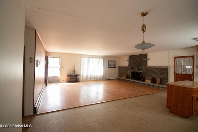 unfurnished living room with a baseboard heating unit, a stone fireplace, and tile patterned floors