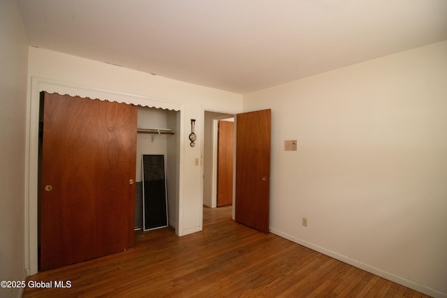 unfurnished bedroom with a closet, baseboards, and wood finished floors