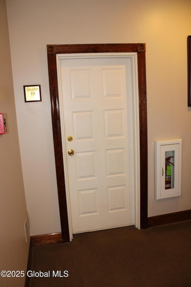 interior space featuring dark carpet and baseboards