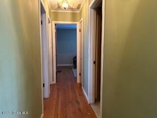 hallway featuring crown molding, wood finished floors, and baseboards