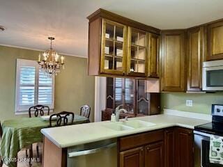 kitchen featuring a sink, stainless steel appliances, light countertops, glass insert cabinets, and hanging light fixtures