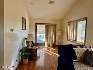 living area with visible vents, wood finished floors, and vaulted ceiling