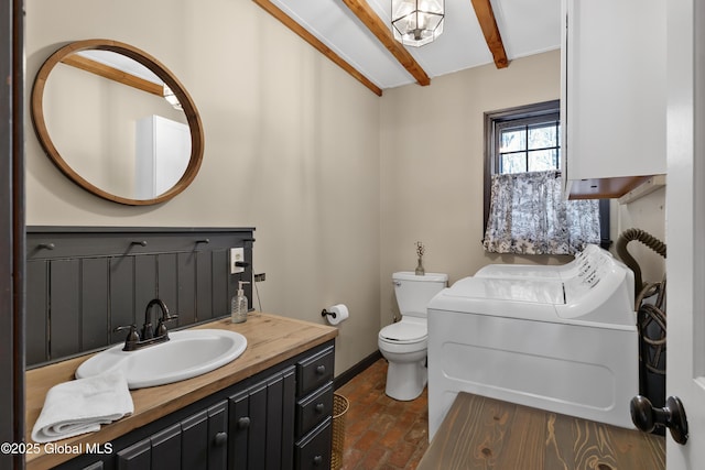 half bathroom featuring beam ceiling, toilet, washer / clothes dryer, baseboards, and vanity