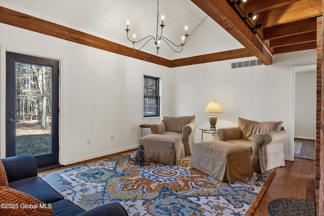 living room featuring visible vents, baseboards, a chandelier, beamed ceiling, and hardwood / wood-style floors