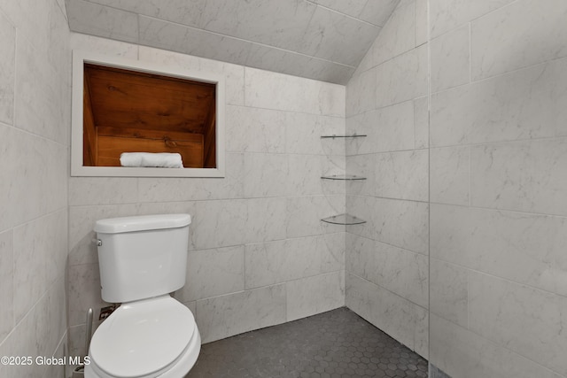 full bath with vaulted ceiling, toilet, and a tile shower