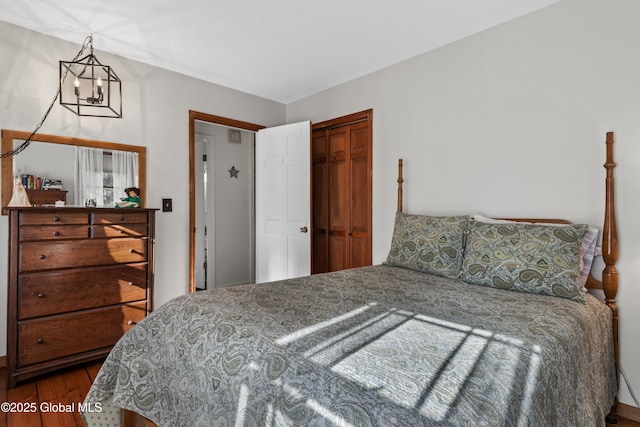 bedroom with a closet, an inviting chandelier, and wood finished floors