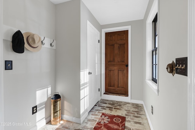 entryway with baseboards and brick floor