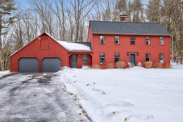 view of front of property featuring an attached garage, a shingled roof, a chimney, aphalt driveway, and board and batten siding