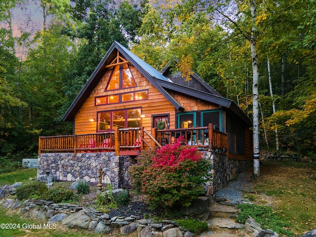 back of property with a forest view and a deck