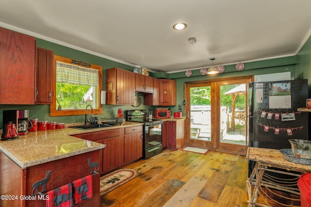 kitchen featuring light stone counters, a sink, light wood-style floors, freestanding refrigerator, and black electric range oven