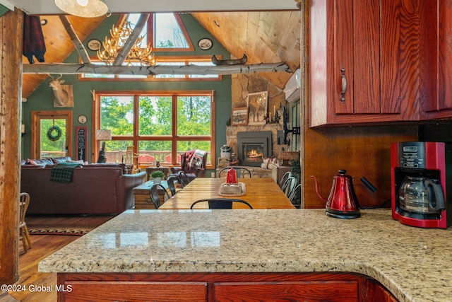 kitchen featuring brown cabinetry, lofted ceiling, open floor plan, wood finished floors, and a fireplace