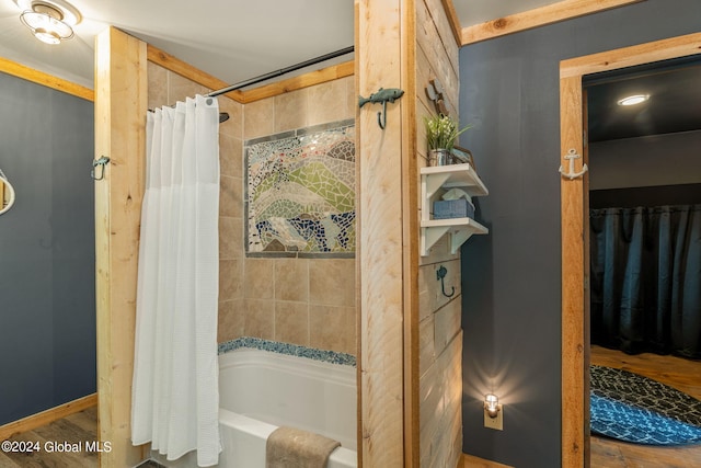 bathroom featuring wood finished floors and shower / bathtub combination with curtain