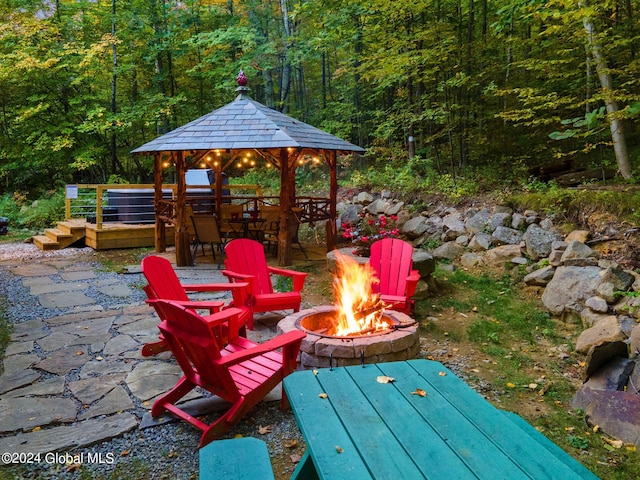 view of patio / terrace with a wooded view, a fire pit, and a gazebo