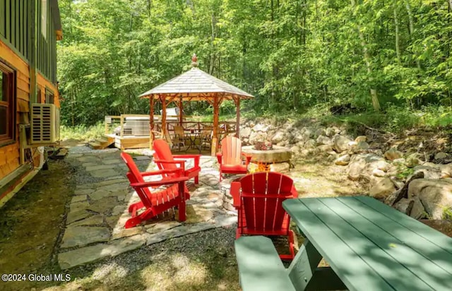 view of patio / terrace featuring a fire pit, a gazebo, and a forest view