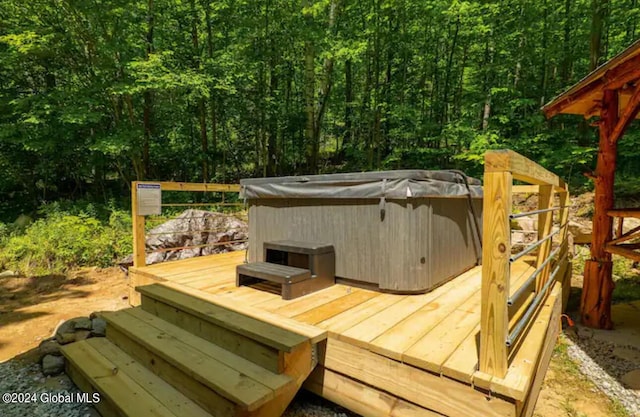 deck featuring a hot tub and a wooded view