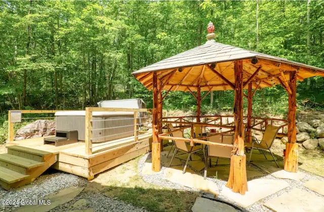 exterior space featuring a gazebo, outdoor dining space, and a forest view