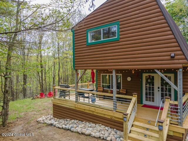 exterior space featuring french doors, log veneer siding, and a deck