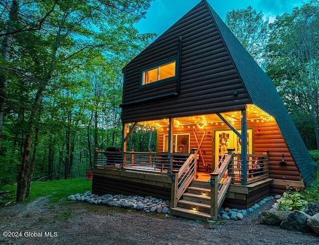 back of house featuring a shingled roof, log veneer siding, and a gambrel roof