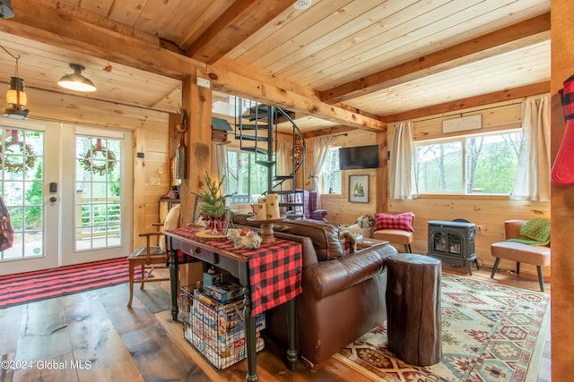 living area featuring beam ceiling, a wood stove, wooden walls, wooden ceiling, and hardwood / wood-style floors