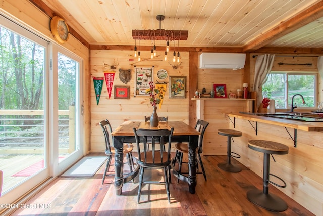 dining room with hardwood / wood-style flooring, a wall unit AC, wooden ceiling, and wooden walls