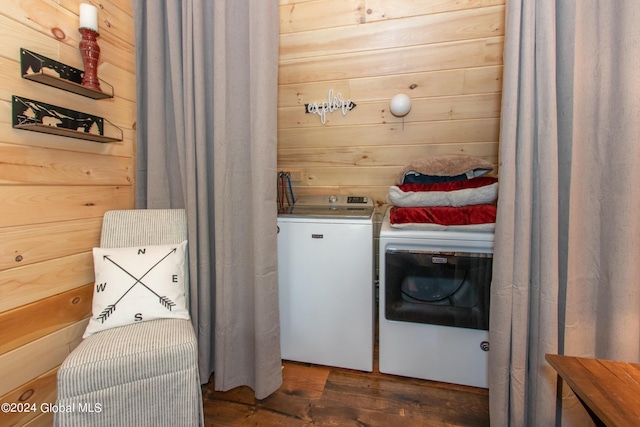 clothes washing area with laundry area, independent washer and dryer, wood walls, and wood finished floors