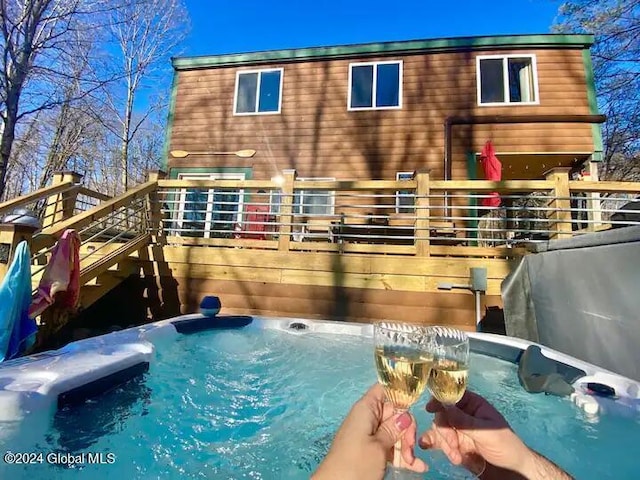 back of property featuring a hot tub, stairway, and a deck