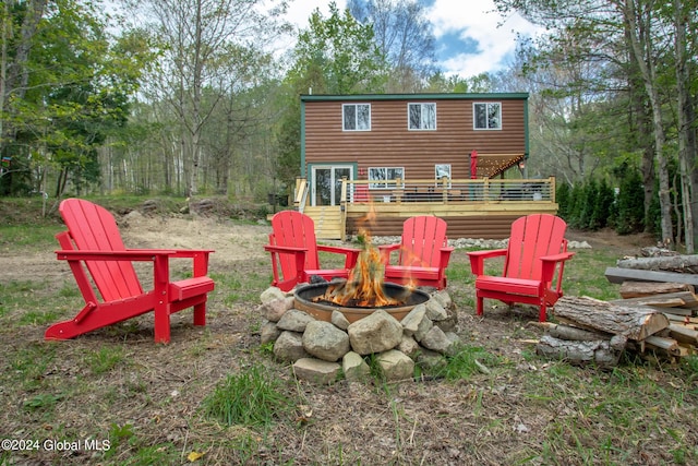 rear view of property with an outdoor fire pit, log veneer siding, and a wooden deck