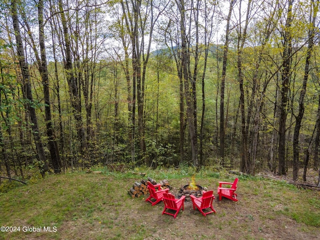 view of yard featuring an outdoor fire pit and a wooded view