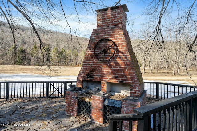 wooden terrace with an outdoor brick fireplace